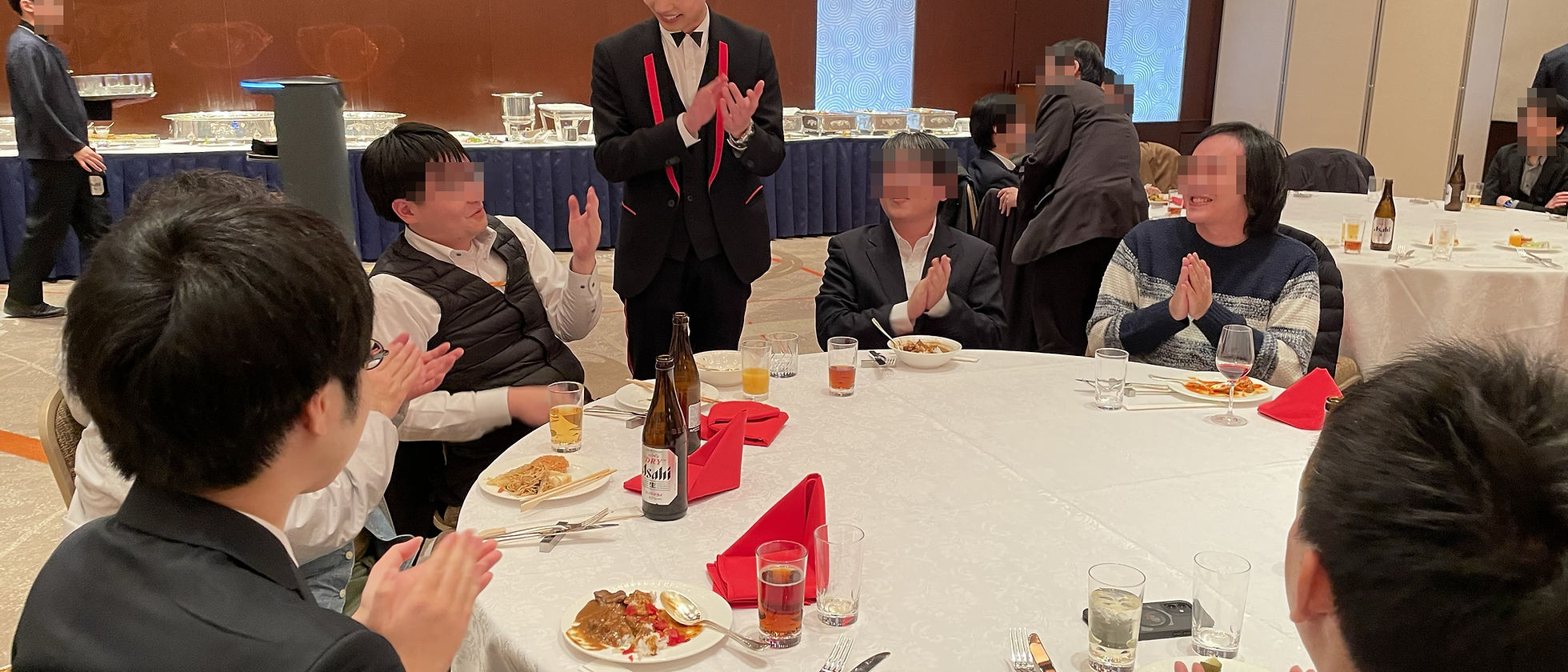 忘年会のテーブルを囲むゲストへマジックを披露する様子